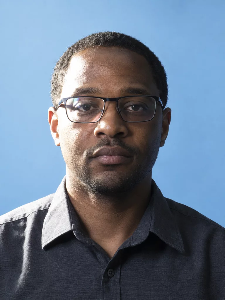 Synthetic portrait before editing, with prescription glasses and strong uneven lighting across the face